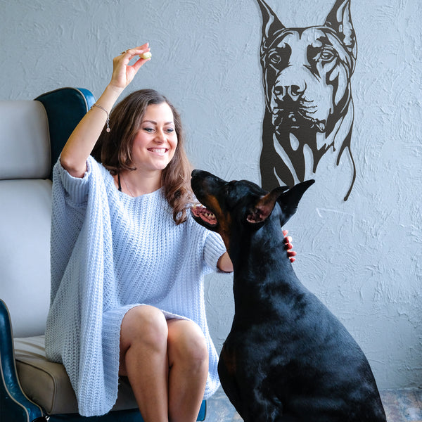Woman with Doberman and metal Doberman wall art in background