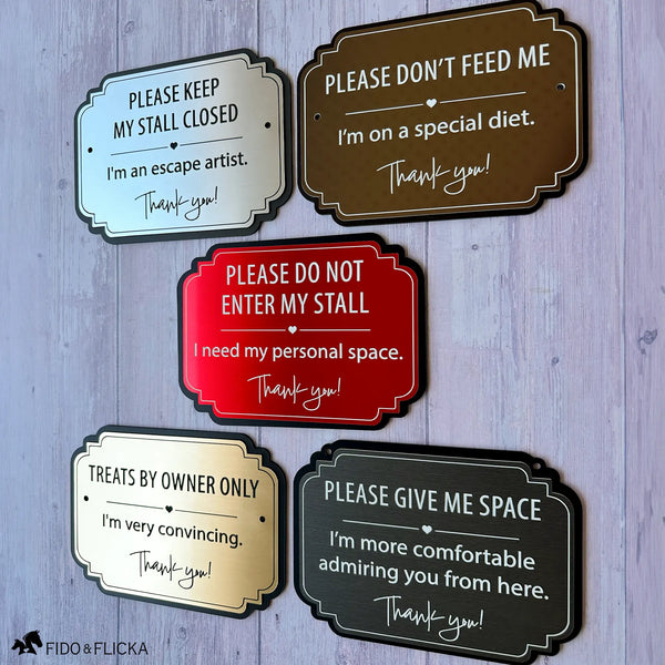 Collection of five metallic horse stall warning signs in silver, bronze, red, gold and charcoal with different safety and care messages.