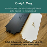 Back side of a black wooden horse stall name plate shown with a white placement guide and brass screws on a wood surface, demonstrating the ready-to-hang installation setup