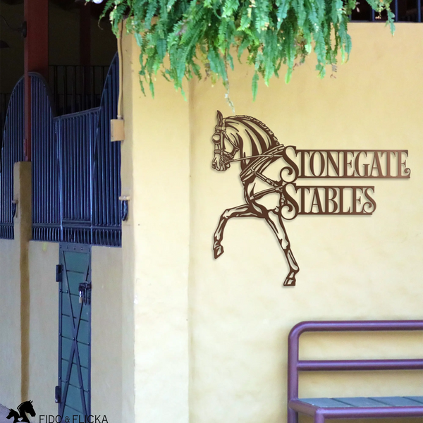 Personalized carriage horse metal sign reading Stonegate Stables mounted on barn wall with stall doors and hanging greenery