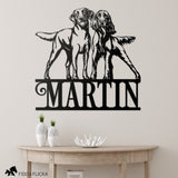 Metal wall art with two dogs and the name 'Martin' on a light gray wall.