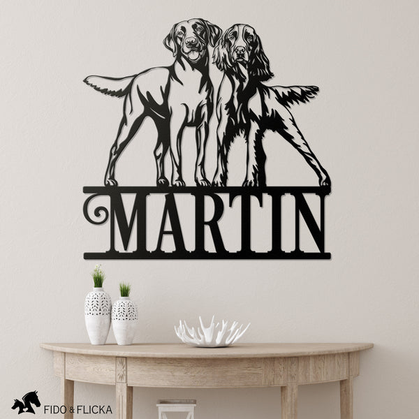 Metal wall art with two dogs and the name 'Martin' on a light gray wall.