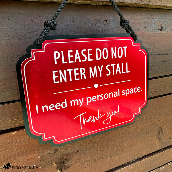 Red horse stall warning sign reading “Please Do Not Enter My Stall, I need my personal space” hanging on a rustic wood stall door