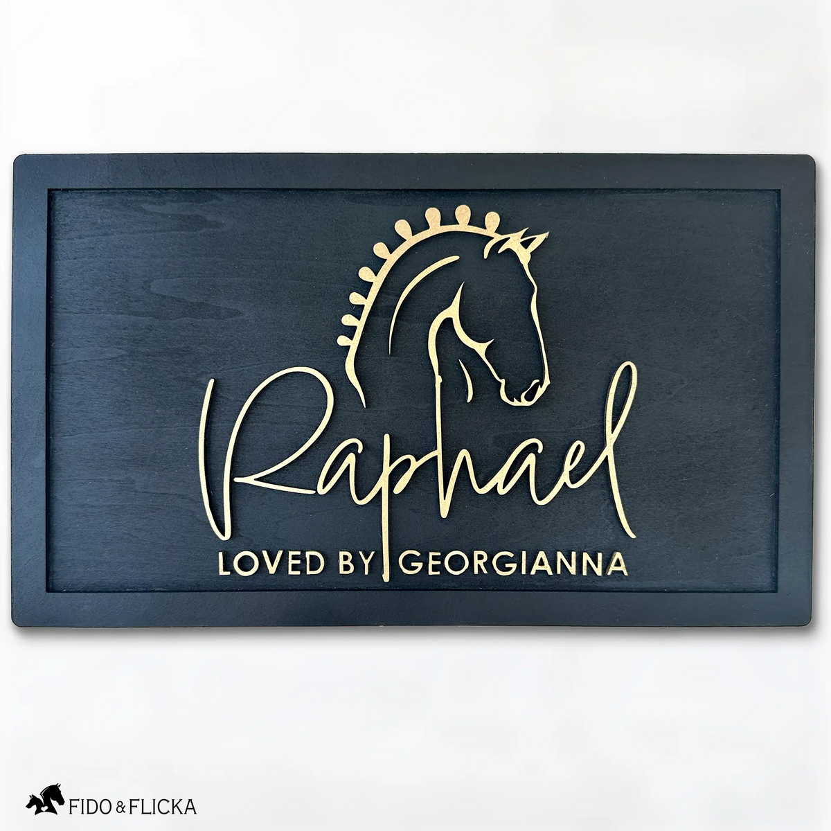 Elegant black wood horse stall nameplate featuring a gold silhouette of a braided show horse and the name “Raphael,” with the inscription “Loved by Georgianna.” Custom equestrian sign by Fido & Flicka, modern and personalized design.