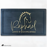 Elegant black wood horse stall nameplate featuring a gold silhouette of a braided show horse and the name “Raphael,” with the inscription “Loved by Georgianna.” Custom equestrian sign by Fido & Flicka, modern and personalized design.