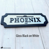 Custom horse stall name plate with raised gloss black acrylic lettering on a white background, framed in black wood and personalized with the name Phoenix.