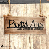 Personalized horse name stall sign reading 'Painted Aria – Loved & Owned by Christina' in black metal on rustic wooden panel, custom barn décor, hanging on horse stall