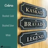 Three personalized horse stall signs showing available color options brushed gold on black reading Kaskade brushed silver on black reading Bravado and white on black reading Legend displayed on warm wood wall by Fido and Flicka