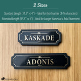 Comparison of two black and gold layered acrylic and wood horse stall name plates showing size options: an 11.5×4 inch sign reading ‘Kaskade’ above a 15.5×4 inch extended-length sign reading ‘Adonis,’ displayed on a light wood background