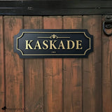 Black and gold layered wood horse stall name plate reading ‘Kaskade,’ mounted on a brown wooden stall door with black metal hardware