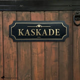 Black and gold layered acrylic and wood horse stall name plate reading ‘Kaskade,’ mounted on a brown wooden stall door with black metal hardware