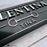 Close-up of a custom horse name plate showing raised silver lettering, Merlot metallic horse bit emblem, and dimensional acrylic details.