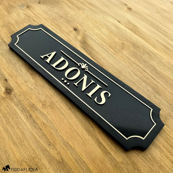 Custom personalized horse stall sign extended 15.5 inch size with raised brushed gold acrylic letters on brushed black acrylic base with sealed black wood frame reading ADONIS