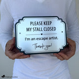 Brushed silver horse stall warning sign reading “Please Keep My Stall Closed, I’m an escape artist,” shown held in two hands for scale.