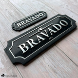 Two matching black acrylic and wood nameplates with silver lettering reading 