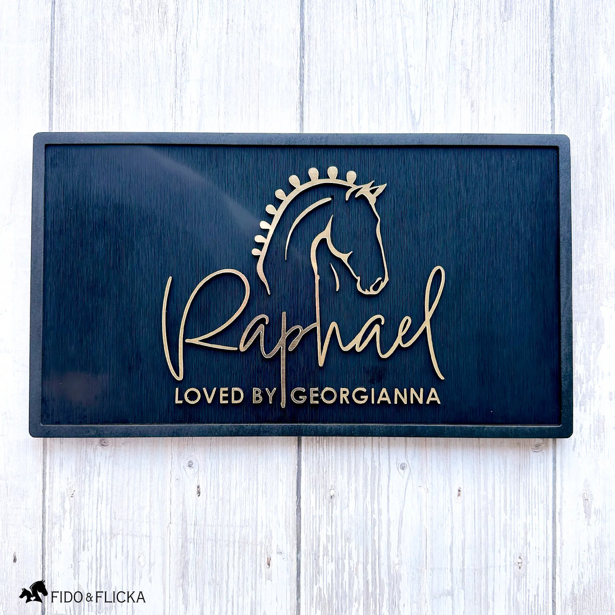 Elegant acrylic and black wood horse stall nameplate featuring a gold silhouette of a braided show horse and the name “Raphael,” with the inscription “Loved by Georgianna.” Custom equestrian sign by Fido & Flicka, modern and personalized design.