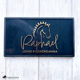 Elegant acrylic and black wood horse stall nameplate featuring a gold silhouette of a braided show horse and the name “Raphael,” with the inscription “Loved by Georgianna.” Custom equestrian sign by Fido & Flicka, modern and personalized design.