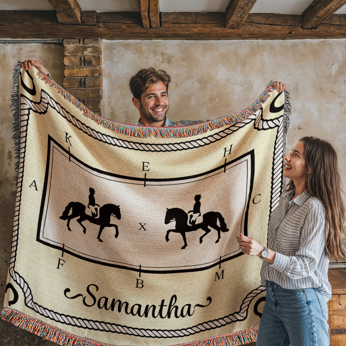 Two people holding a decorative blanket with dressage horse designs and the name 'Samantha'.