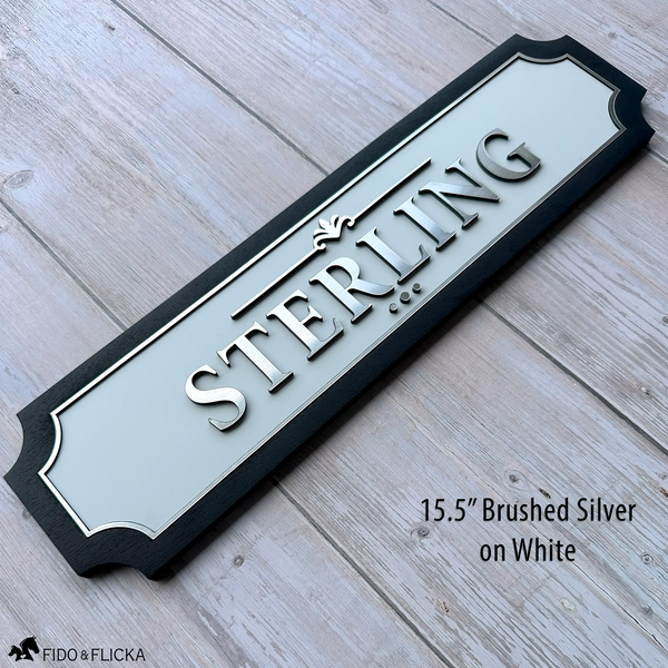 Personalized horse stall sign 15.5 inch extended size with raised brushed silver acrylic letters spelling STERLING on white acrylic base panel with sealed black wood frame by Fido and Flicka