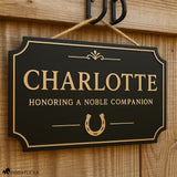 Custom horse stall sign in layered Baltic birch wood with gold on black finish, personalized name plaque with horseshoe design hanging on barn door.