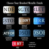 A product options chart titled 'Choose Your Brushed Metallic Finish' showing nine finish/color samples for custom text plates: gold, silver, copper, bronze black text, bronze white text, blue, charcoal black text, charcoal white text, and red. The bottom shows a red sample with partial text 'ER MY S' and a note about messaging.