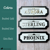 Three personalized horse stall signs on barn wall showing white acrylic color options brushed gold reading Aurora brushed silver reading Sterling and gloss black reading Phoenix with black wood frame by Fido and Flicka