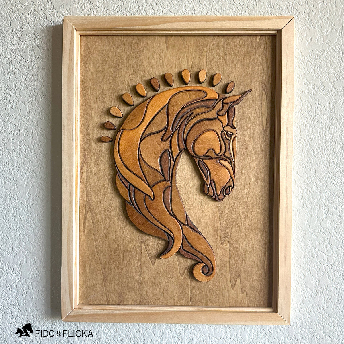 Frontal view of a handcrafted wood horse head wall art featuring layered, stained wooden pieces forming a Baroque-style design. The artwork is framed in natural wood and displayed against a lightly textured wall, highlighting the detailed contours and warm tones of the sculpture.
