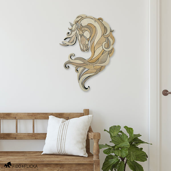 Wooden wall art of a horse head on a white wall above a wooden bench with a white pillow and a plant.